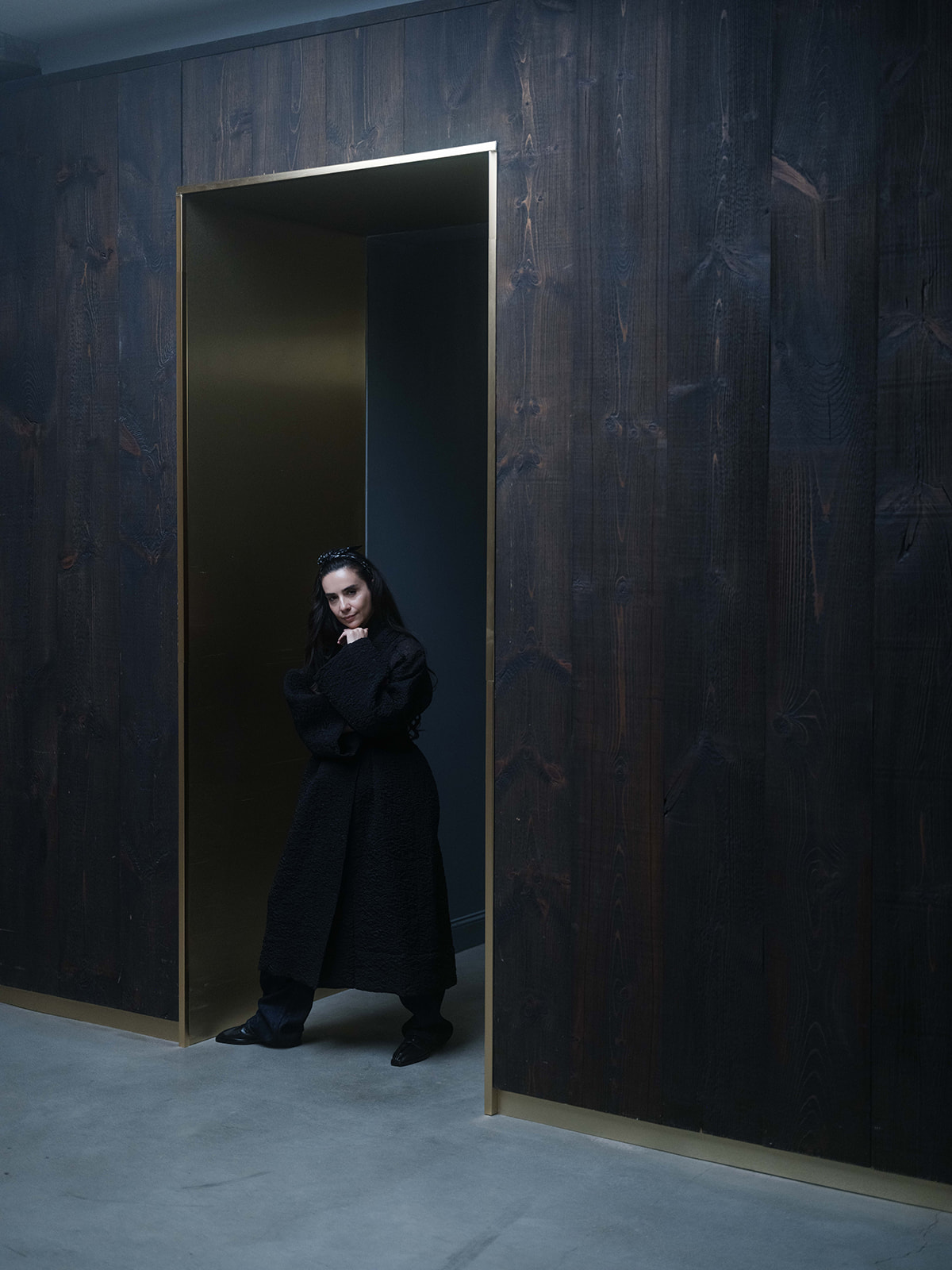 Bela Shehu standing in a tall doorway framed by dark wood and brass