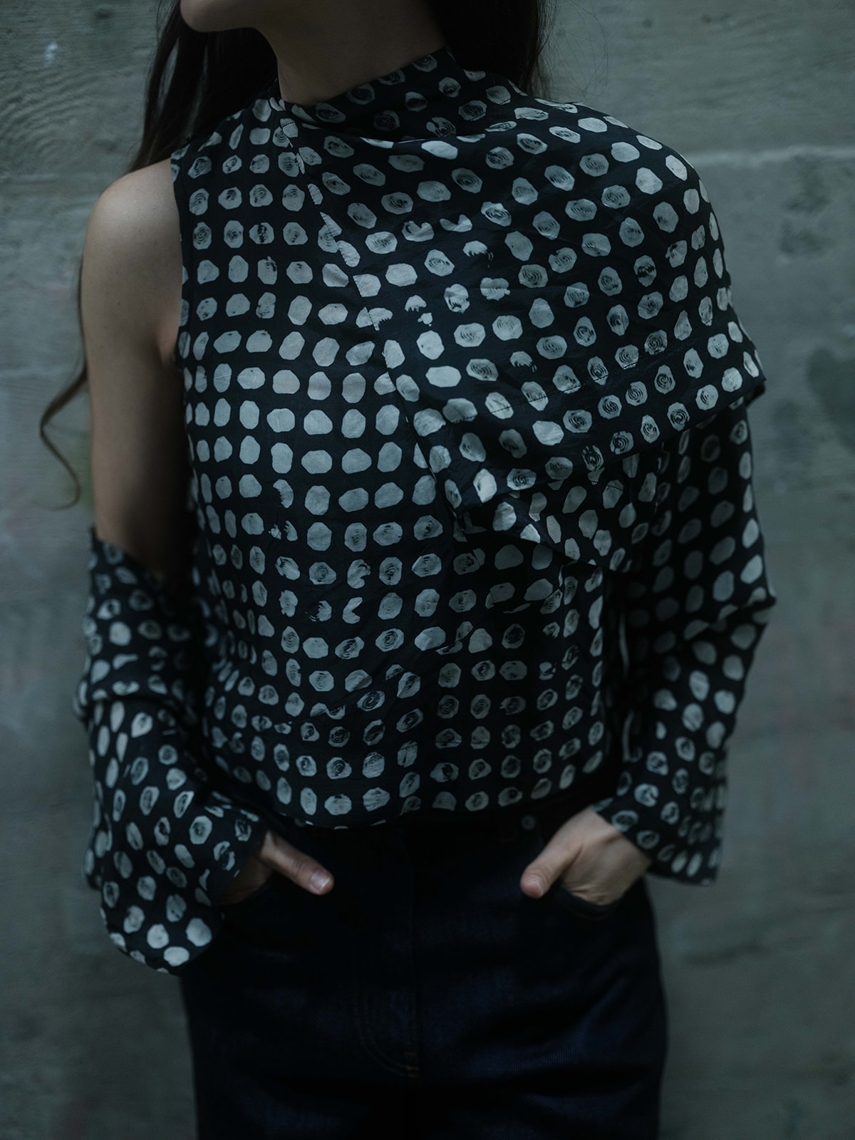 Close view of an asymmetrically constructed patterned blouse with hands in pockets